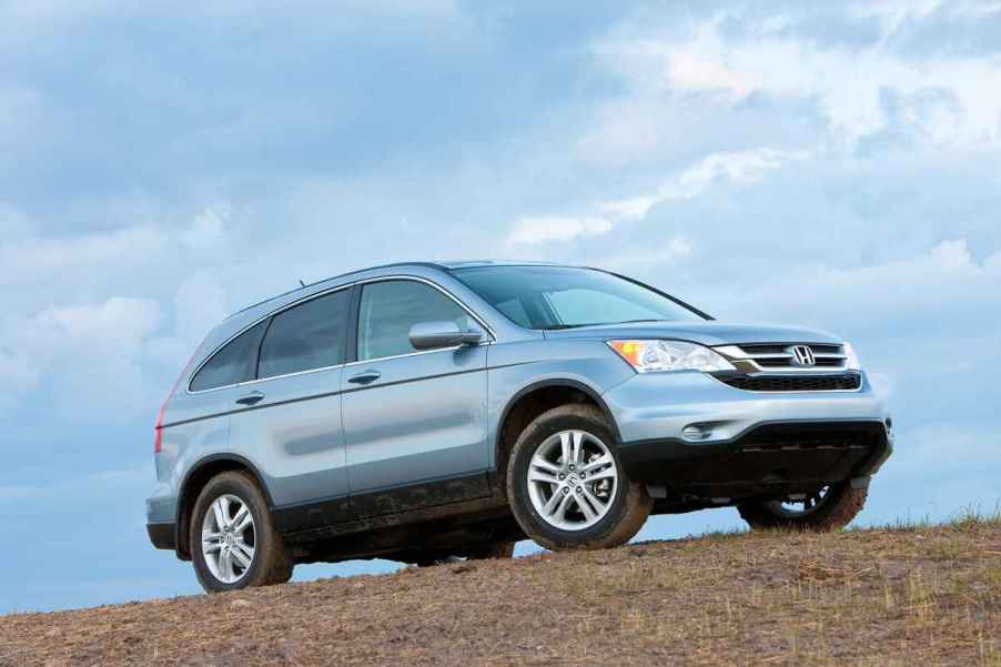 A blue 2010 Honda CR-V parked on a dirt hill in right front angle profile view