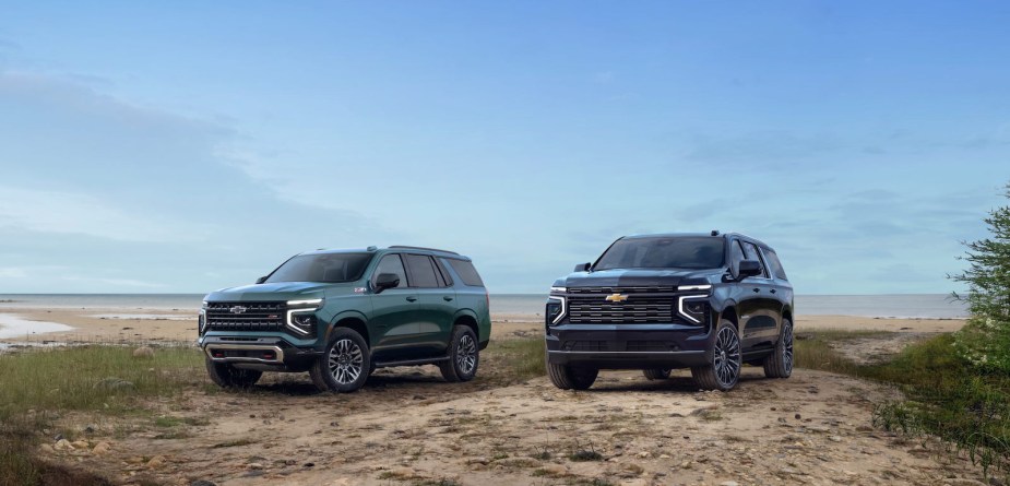 Two black Chevrolet SUVs parked on a beach