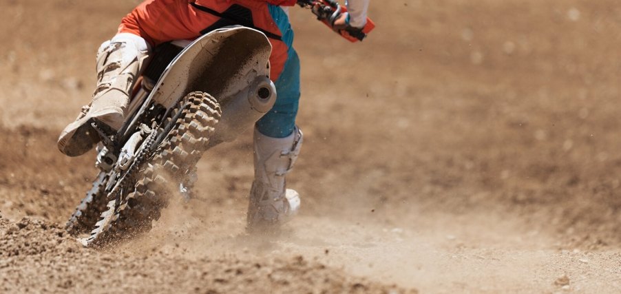 A closeup shot shows a person taking a ride on a dirt bike on a trail instead of the road.