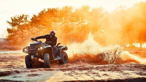 An ATV rider kicks up dirt as they slide their all-terrain vehicle. But they likely can't drive an ATV on the road.