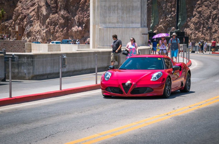 Red Alfa Romeo 4C driving across a dam.