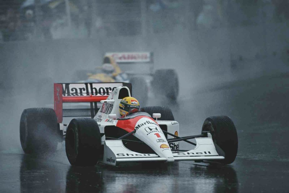 Ayrton Senna's #1 McLaren F1 car sliding across a rain-covered F1 track