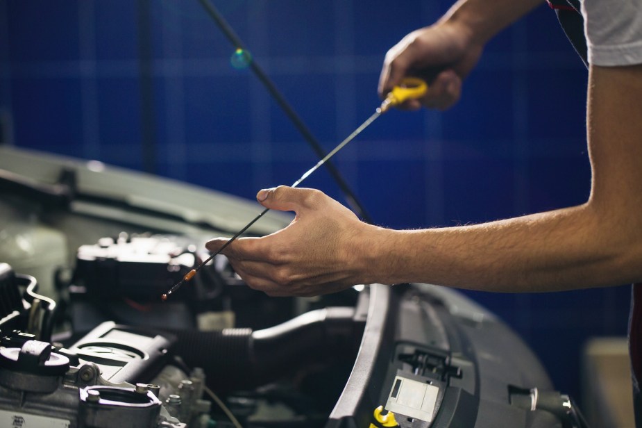 A car owner checking their engine oil level with a dipstick