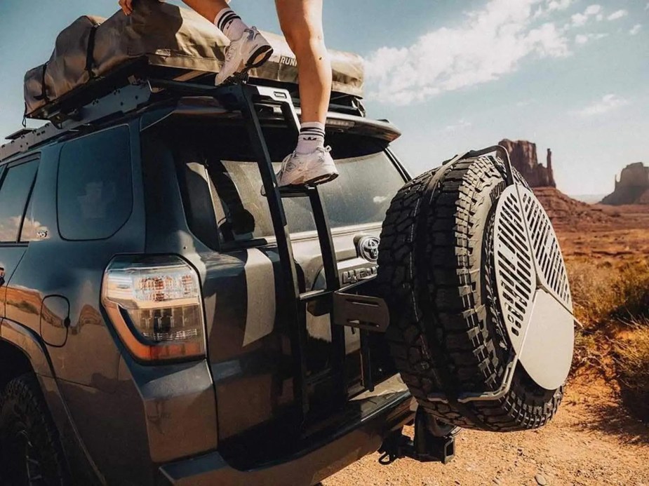 Man climbs the roof ladder of a 4Runner SUV.