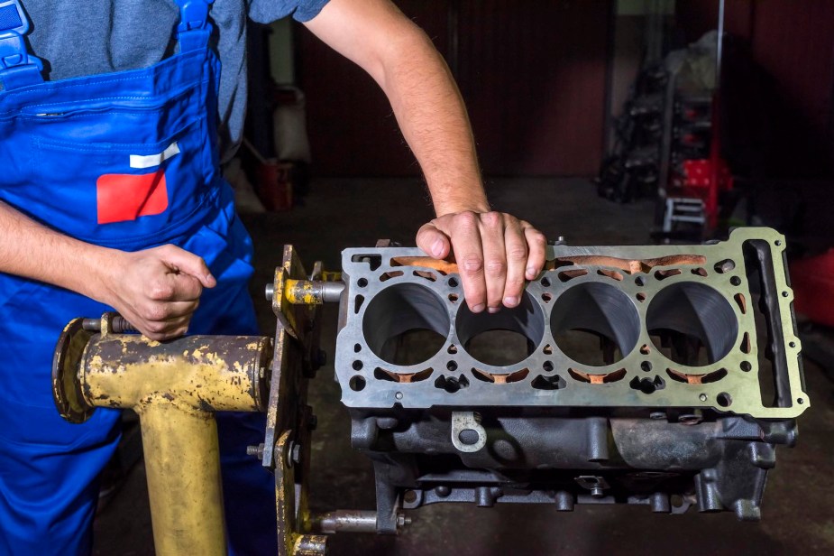 Mechanic places a hand on a V8 engine block on an engine stand.