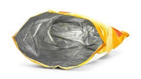 Bright yellow potato chip bag, empty and sitting on a white background.