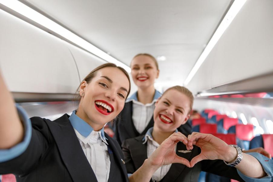 Flight attendants smile and pose for a smartphone picture.