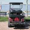 The back of a golf cart parked facing a lake, next to a "golf cart parking only" sign.