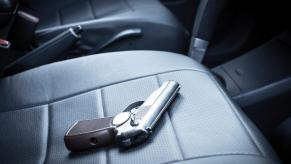 A gun sits in a car on the passenger seat.