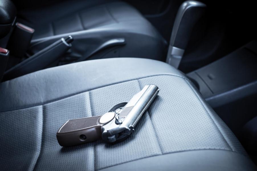 A gun sits in a car on the passenger seat.