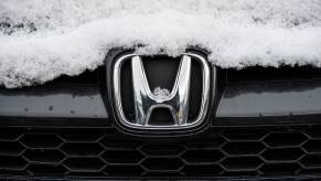 The Honda logo on the grille of a snow-covered SUV