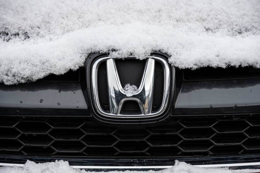 The Honda logo on the grille of a snow-covered SUV