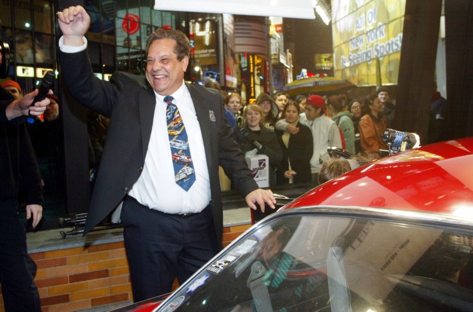 Irving Gordon stands next to his red 1966 Volvo P1800s with his fist in the air