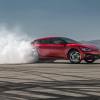 A red Kia EV6 GT creates tire smoke on a pad.