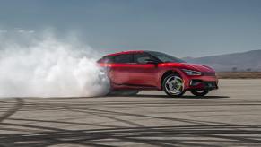 A red Kia EV6 GT creates tire smoke on a pad.