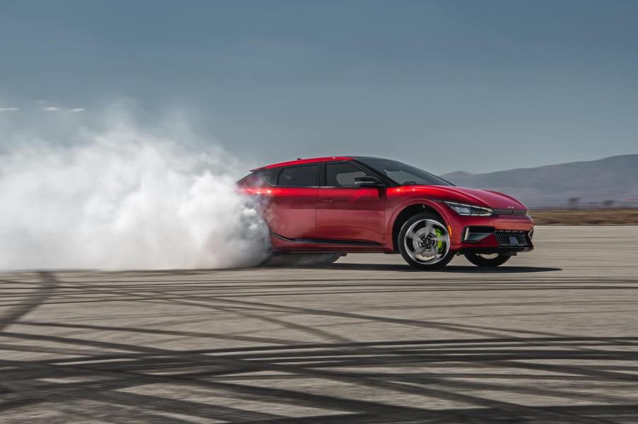 A red Kia EV6 GT creates tire smoke on a pad.