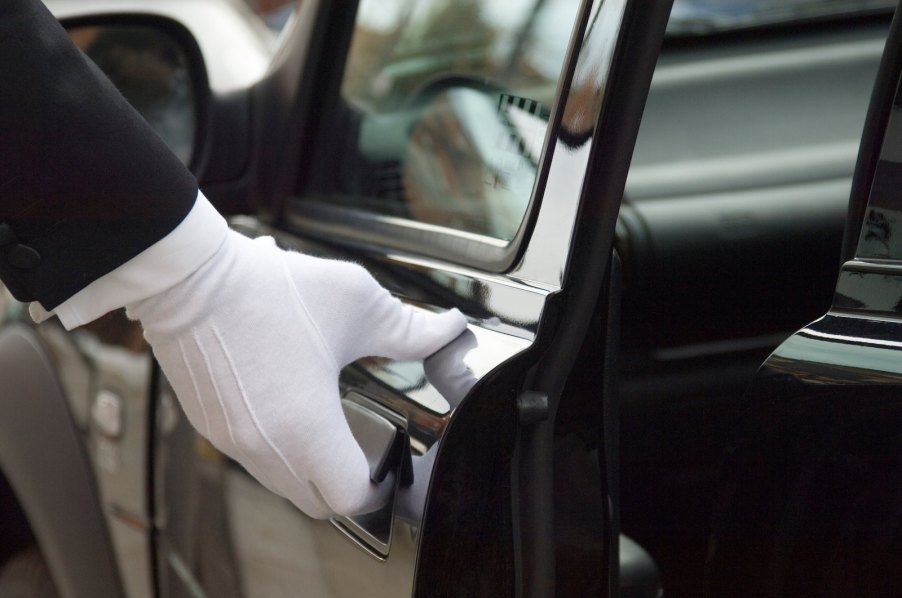 Chauffeur in white gloves opens a limousine door