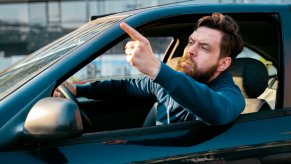 Frenchman pointing his finger out his window during traffic.