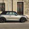 Gray mini cooper convertible with a black top parked on a city street.