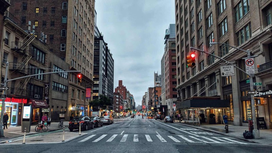 Red traffic light above an empty street in a New York City neighborhood.