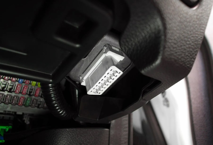 White plastic OBD port under a car's dashboard.