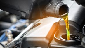 Closeup of oil pouring into an engine as a mechanic completes a change.