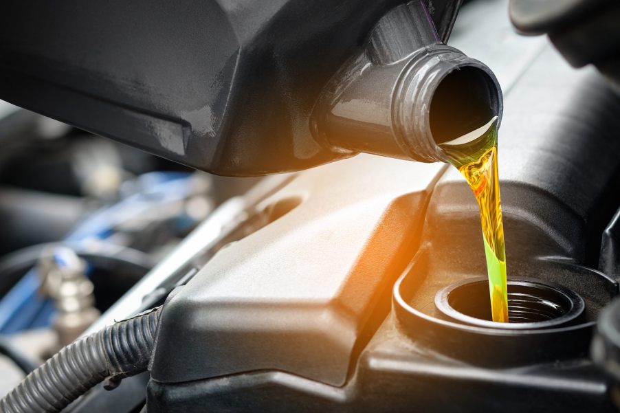 Closeup of oil pouring into an engine as a mechanic completes a change.