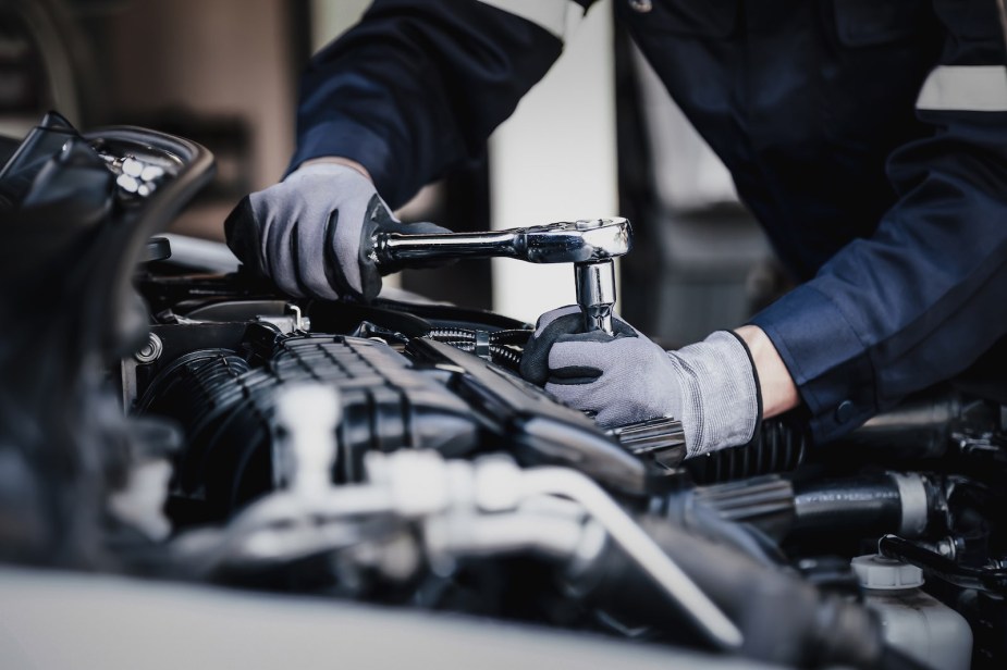 The hands of an auto mechanic as he repairs an old car.