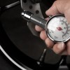 Man uses a tire pressure gauge to check his psi in hot summer weather.