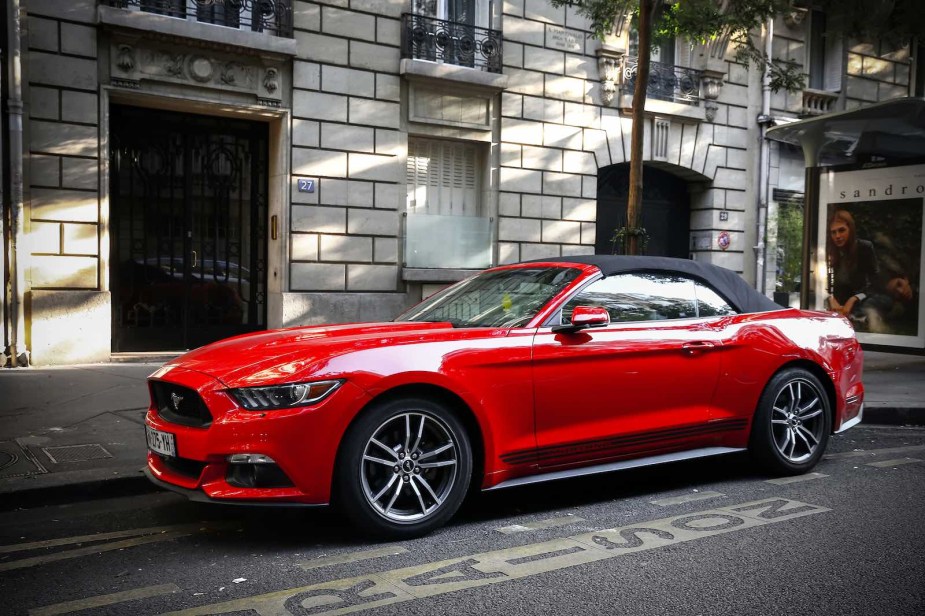 Red Ford Mustang convertible parked on a city street.