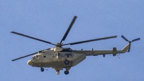 Russian-built Mi-8 helicopter flying in front of a blue sky.