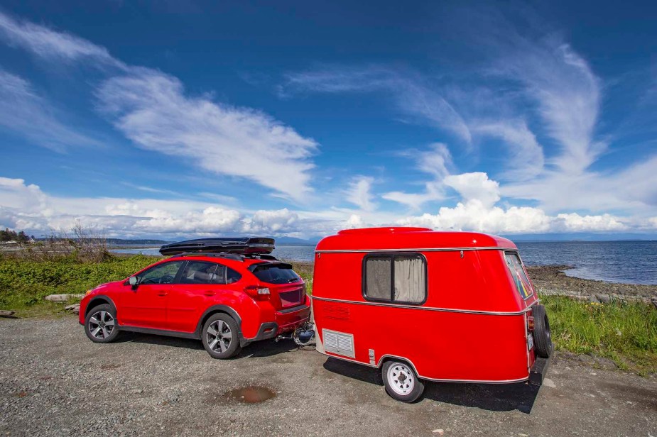 Red Subaru towing a travel trailer, on the beach in Vancouver.