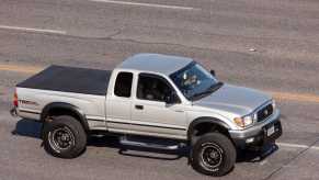 Silver Toyota pickup truck driving down the highway.