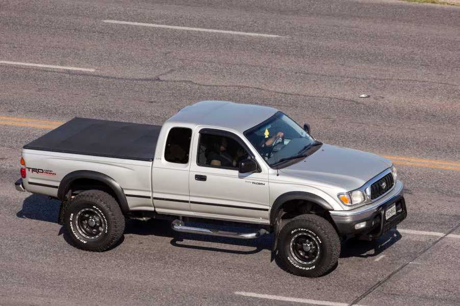 Silver Toyota pickup truck driving down the highway.