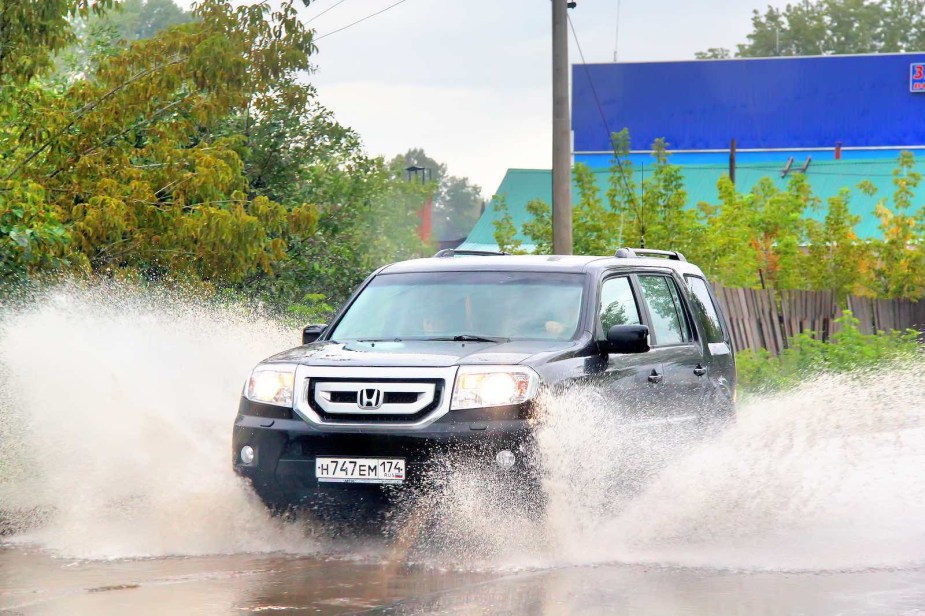 Used Honda Pilot SUV driving through a puddle of water.