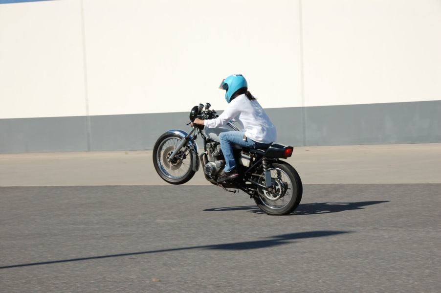 A motorcycle rider performs a wheelie.