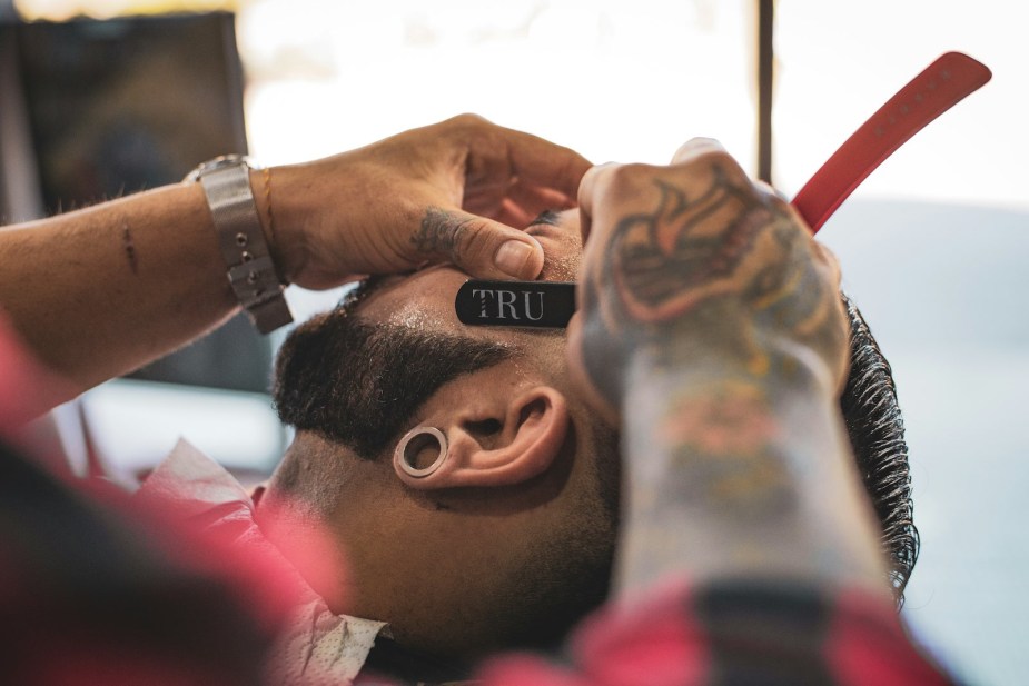 Barber lines up a beard during a haircut.