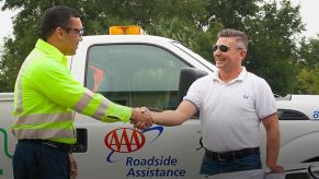 A AAA roadside assistance specialist helps a driver on the side of the road.