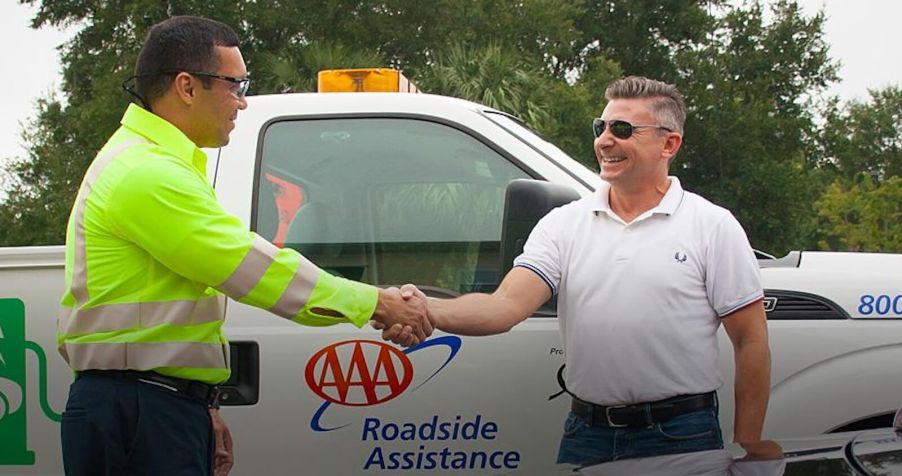 A AAA roadside assistance specialist helps a driver on the side of the road.