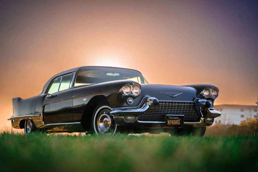 A black 1958 Cadillac Eldorado Brougham parked on grass in right front angle view with sun barely peeking over roofline