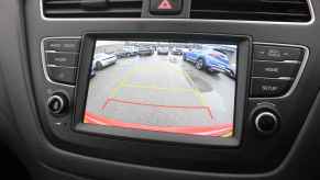 A car backup camera screen in close view showing yellow and red grid lines parking lot