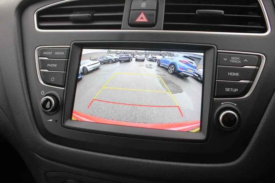 A car backup camera screen in close view showing yellow and red grid lines parking lot