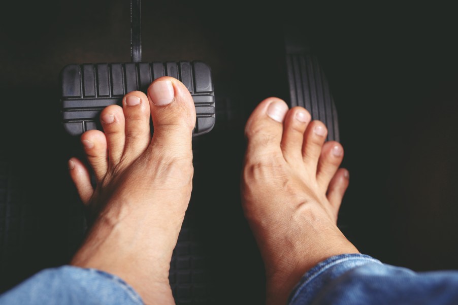 Two bare feet touching car pedals