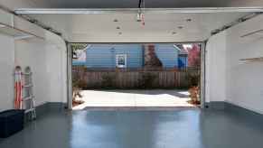 The view from inside a cleaned out garage with the door open gray painted floor folded up ladder on left side