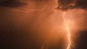 Orange lightning bolts striking a black-colored sky and clouds