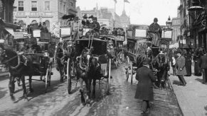 A black and white image of London traffic circa 1870 featuring horse drawn carriages and pedestrians