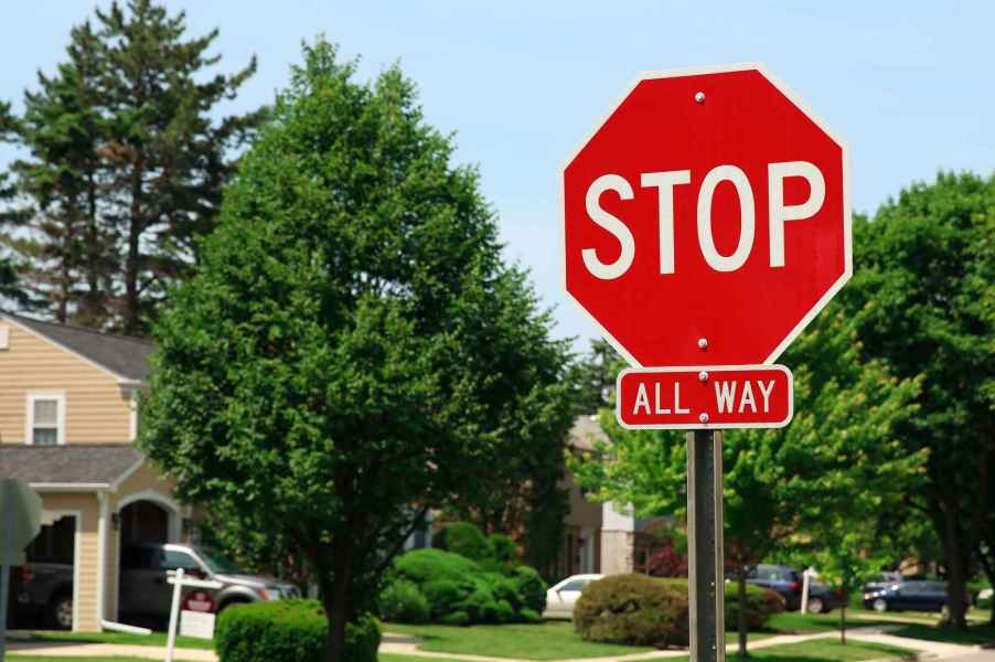 A red stop sign with "ALL WAY" posted under it at a residential intersection