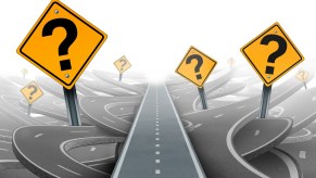 An illustration with a group of street signs with bold question marks peppered around roads winding around the lower and mid frame