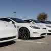 A line of white Tesla EVs parked in right front angle view in parking spots