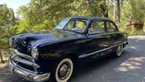 A black 1949 Ford car parked in left front angle view